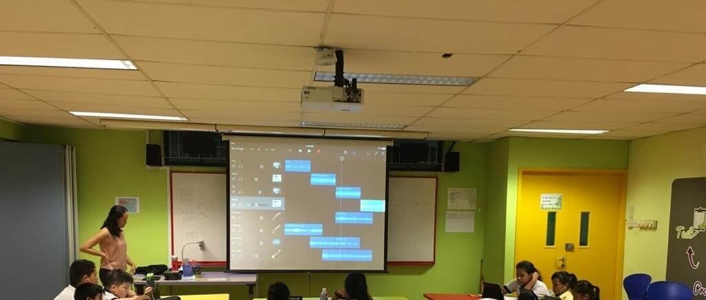 A GarageBand project with several tracks projected on a screen at the front of a classroom.